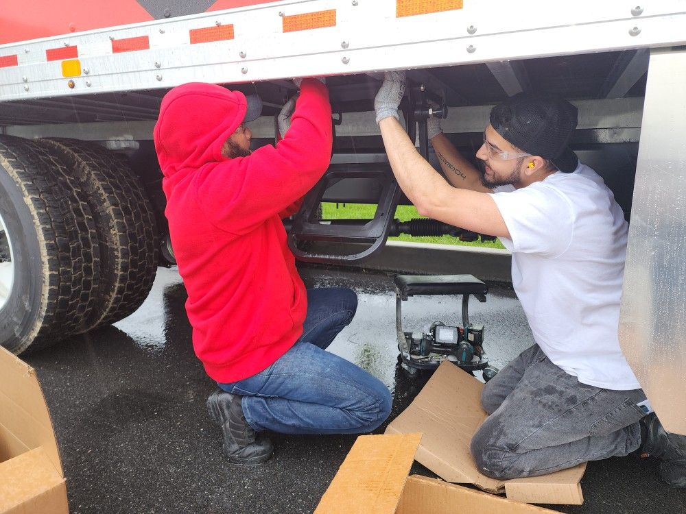 Technicians servicing trailer undercarriage