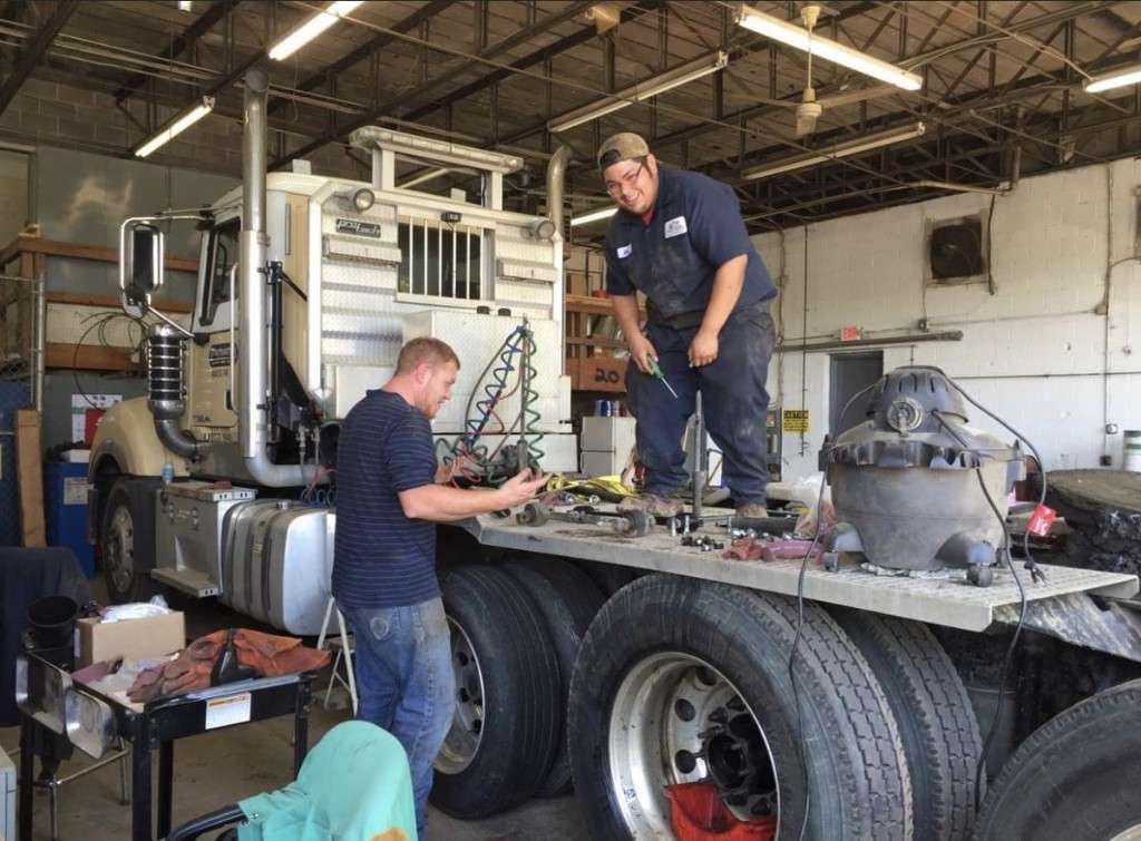 Mechanics coordinating work on a white tractor